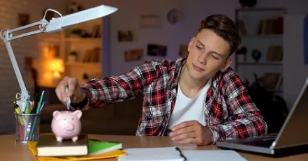 Teenage boy putting money in a piggy bank
