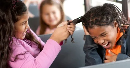 Girl pulling another girls hair on a school bus