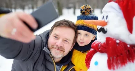 Man and boy taking picture with a snowman
