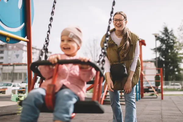 Mother pushing daughter on swing