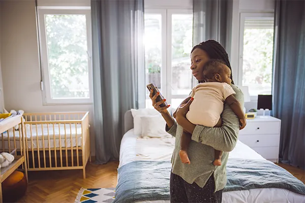 Mother holding baby looking at phone