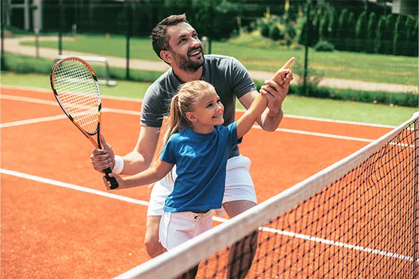 Father helping daughter practiice tennis