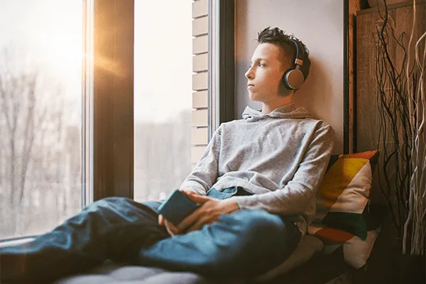 Teen boy listening to music while looking out a window