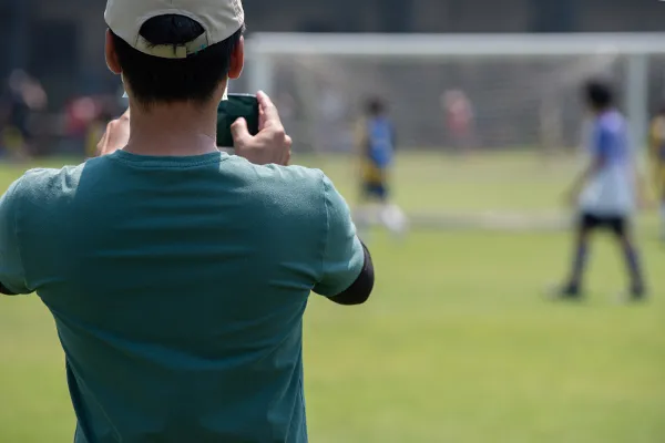 Father taking photos of child at soccer game