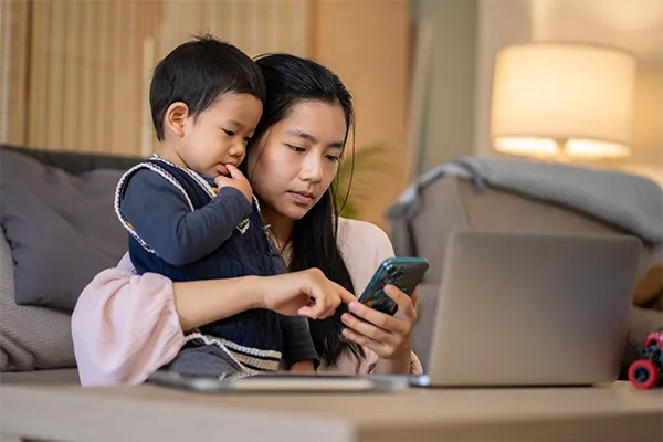 Mother holding toddler texting