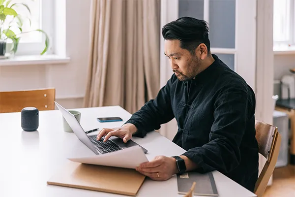 A man comparing documents and computer notes