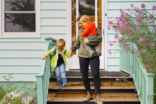Mother holding a child helping another down stairs
