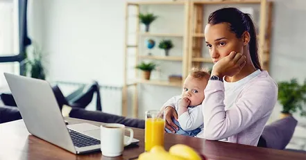 Worried mother holding baby looking at computer