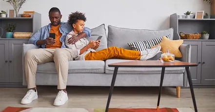 Father on couch with son looking at phone