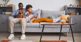 Father on couch with son looking at phone