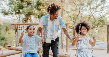 Father pushing children on swings