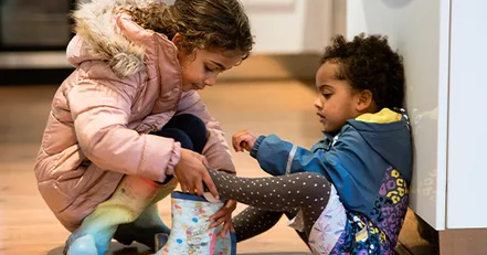Siblings helping each other put shoes on