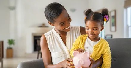 Woman showing her daughter a piggy bank