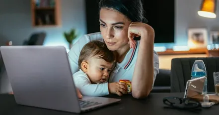Mother holding infant looking at a computer
