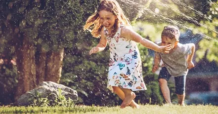 Children running through sprinklers