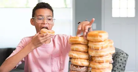 Child eating multiple donuts