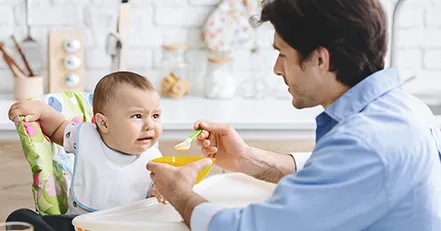 Father trying to feed a baby